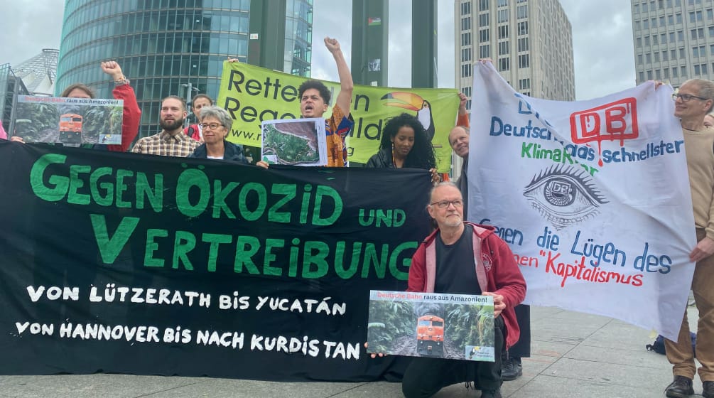 Manifestación en Potsdamer Platz, Berlín, frente a la sede de DB, mayo 2024 Un grupo de personas protesta con grandes pancartas de varias organizaciones, delante de unos edificios